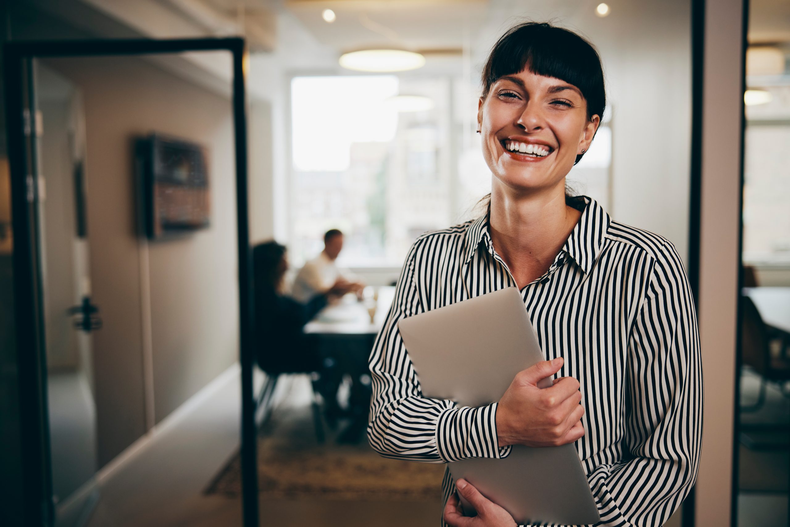 Woman smiling while holding her laptop.