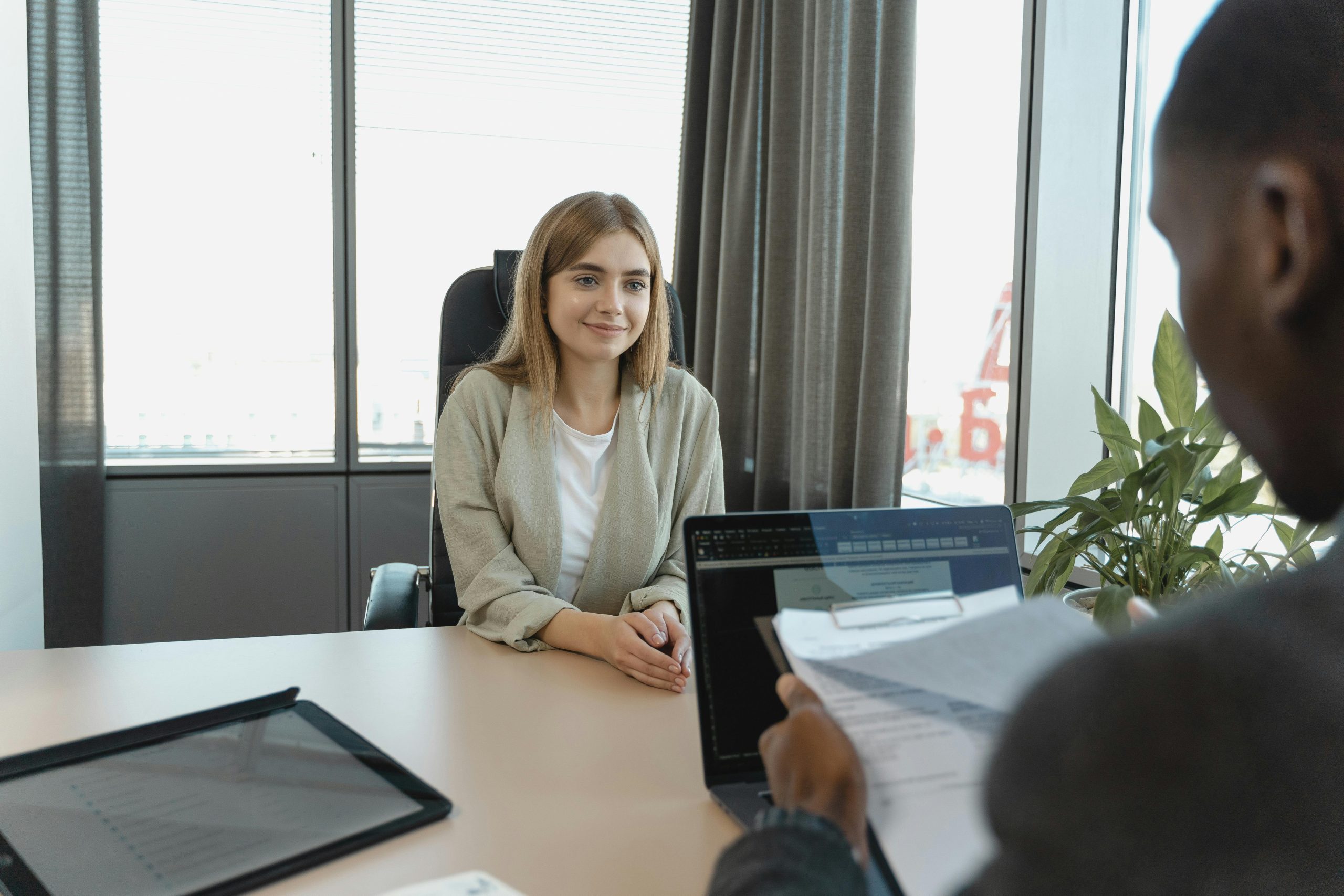 Woman sitting at a desk during a job interview. She is smiling